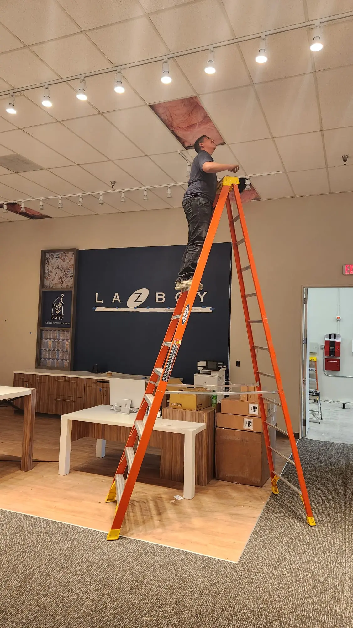 Vicente of Martinez Electric Corp installing track lighting at La-Z-Boy commercial showroom