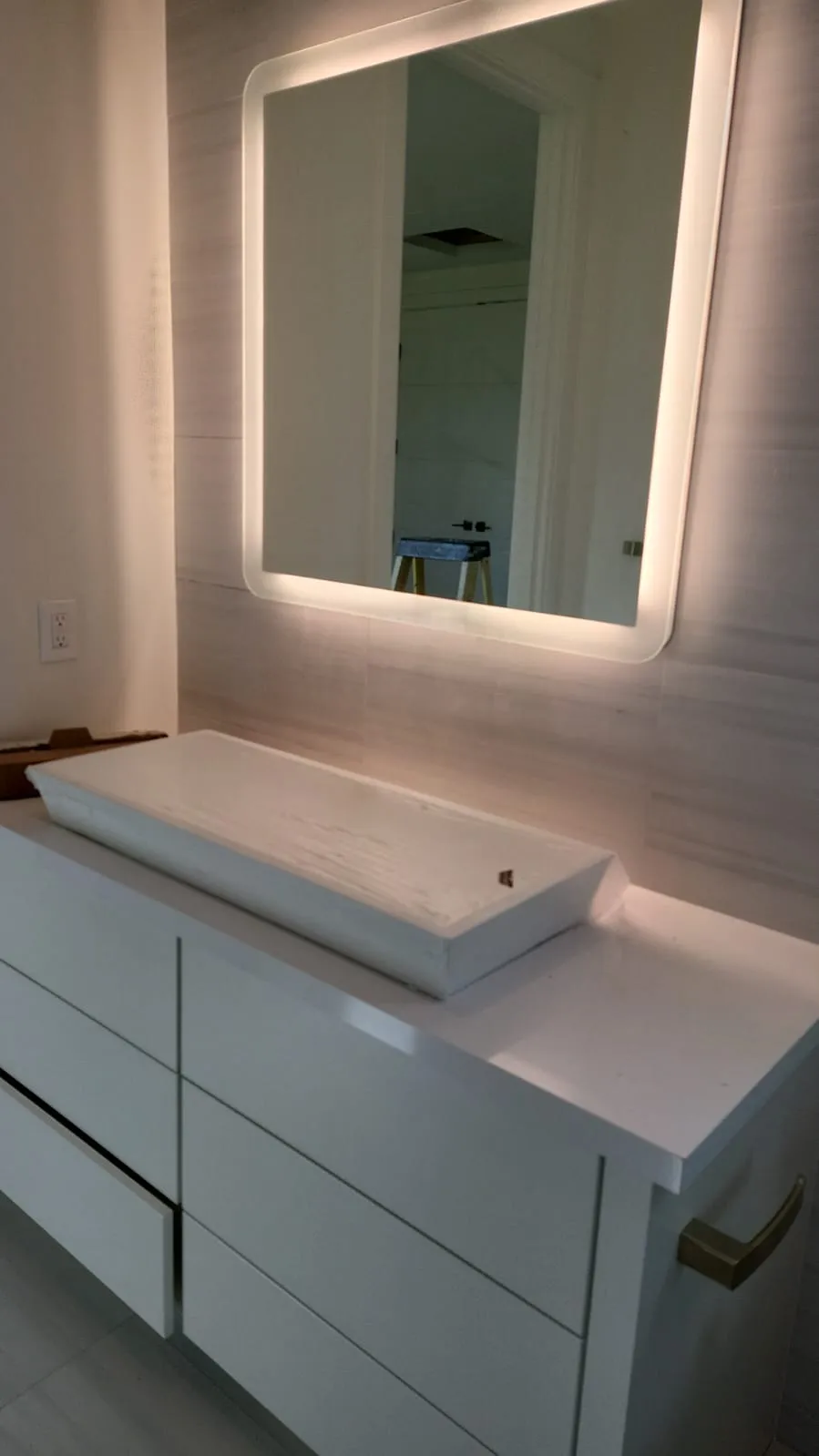Modern LED edge-lit mirror over white floating vanity. Martinez Electric Corp