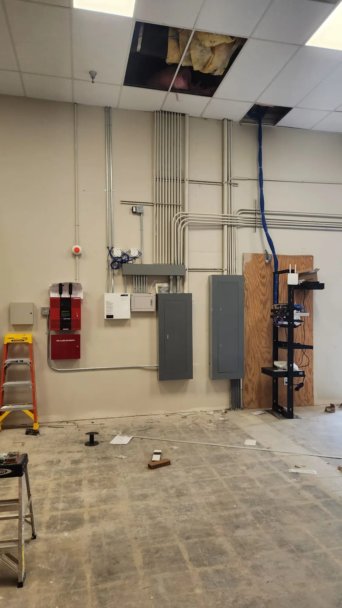 Espacio industrial con red de conduit en techo, paneles eléctricos y sistema de alarma. Martinez Electric Corp