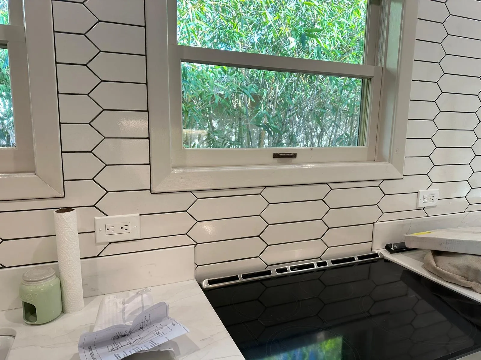 Outlet flush-mounted in white picket-tile backsplash next to electric range. Martinez Electric Corp