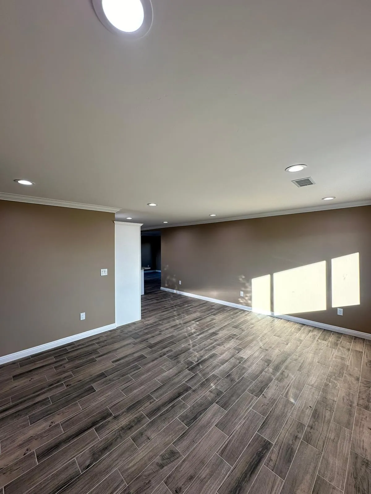 Empty living space with brown walls and distributed recessed ceiling lighting. Martinez Electric Corp