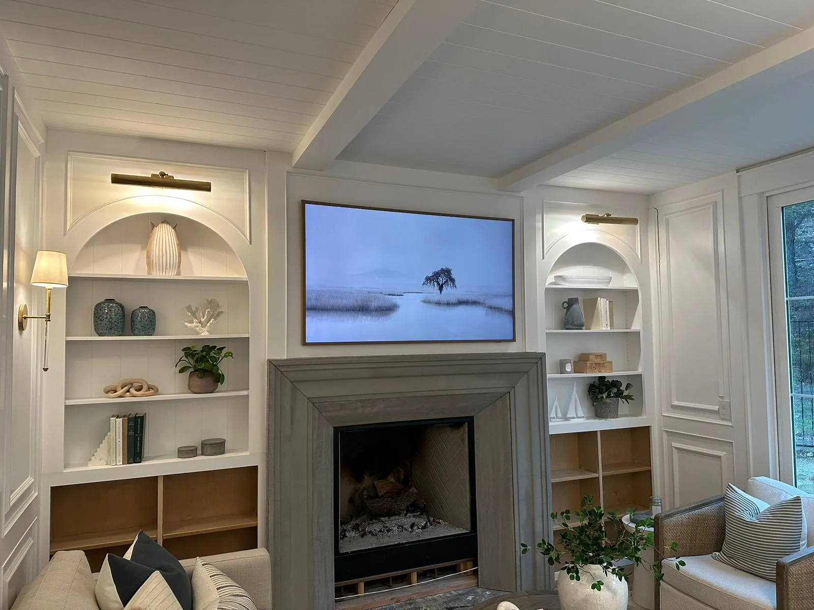 Sala con chimenea, librero empotrado y picture lights de bronce instalados por Martinez Electric Corp