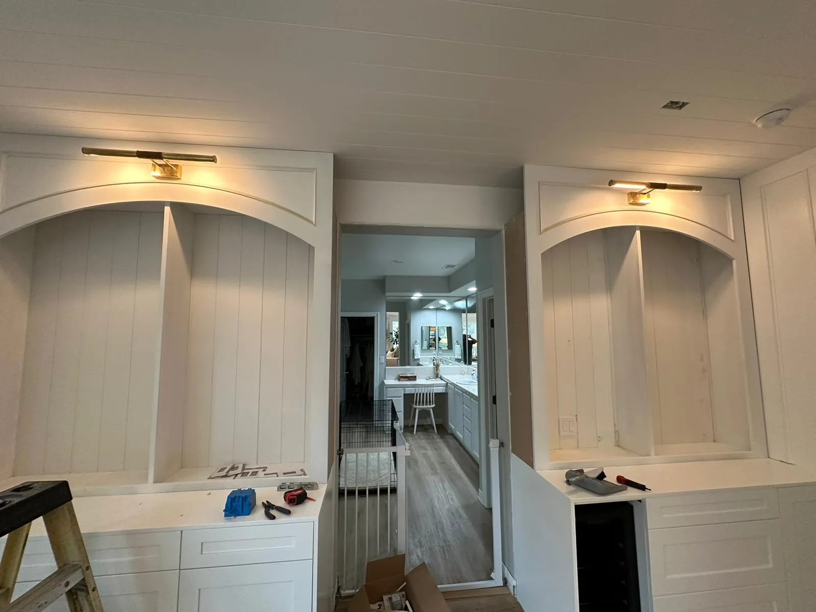 Arched built-in cabinets with brass picture lights. Installation in progress by Martinez Electric Corp