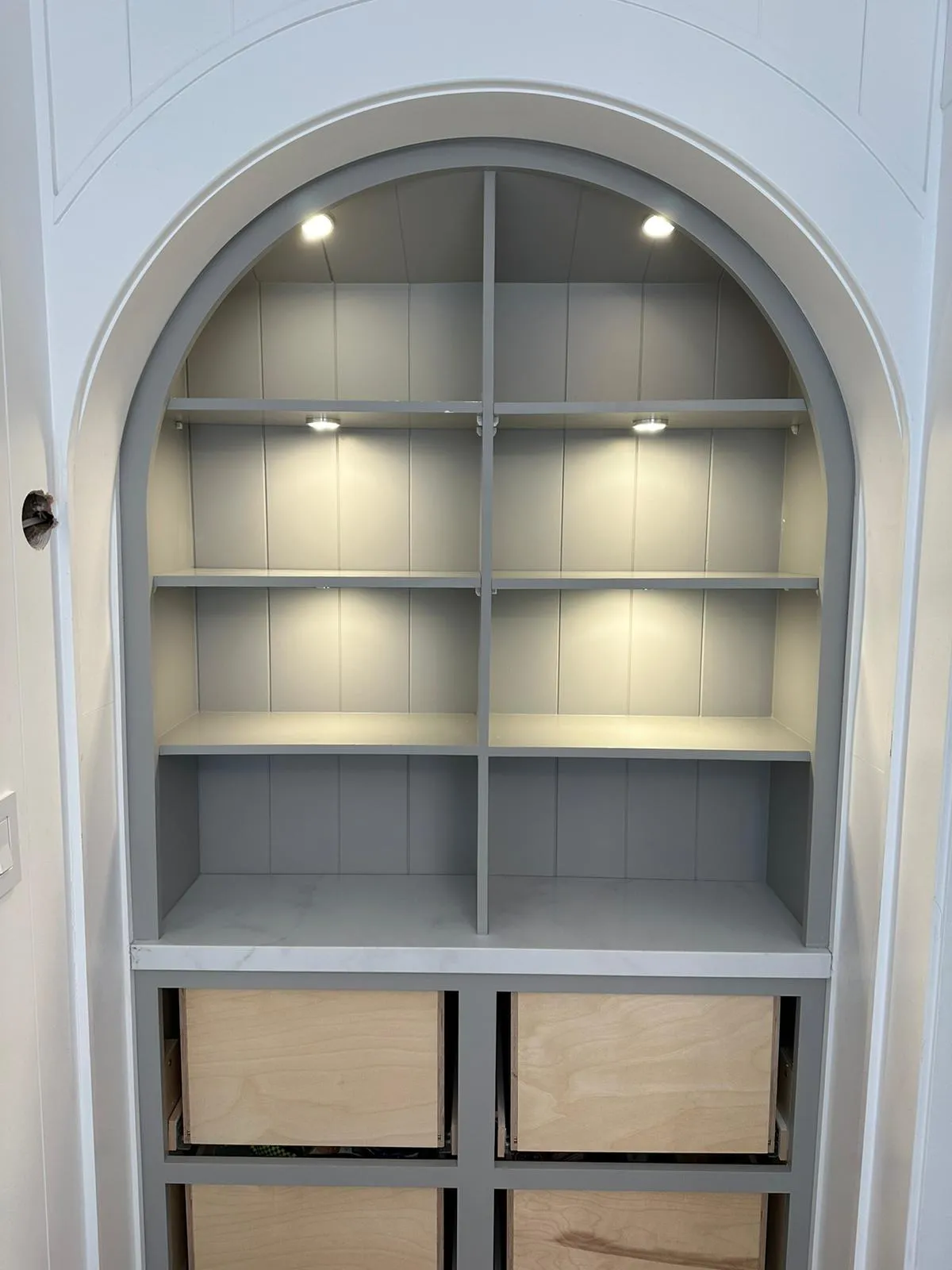 Arched built-in shelving with under-shelf puck lights. Architectural lighting by Martinez Electric Corp