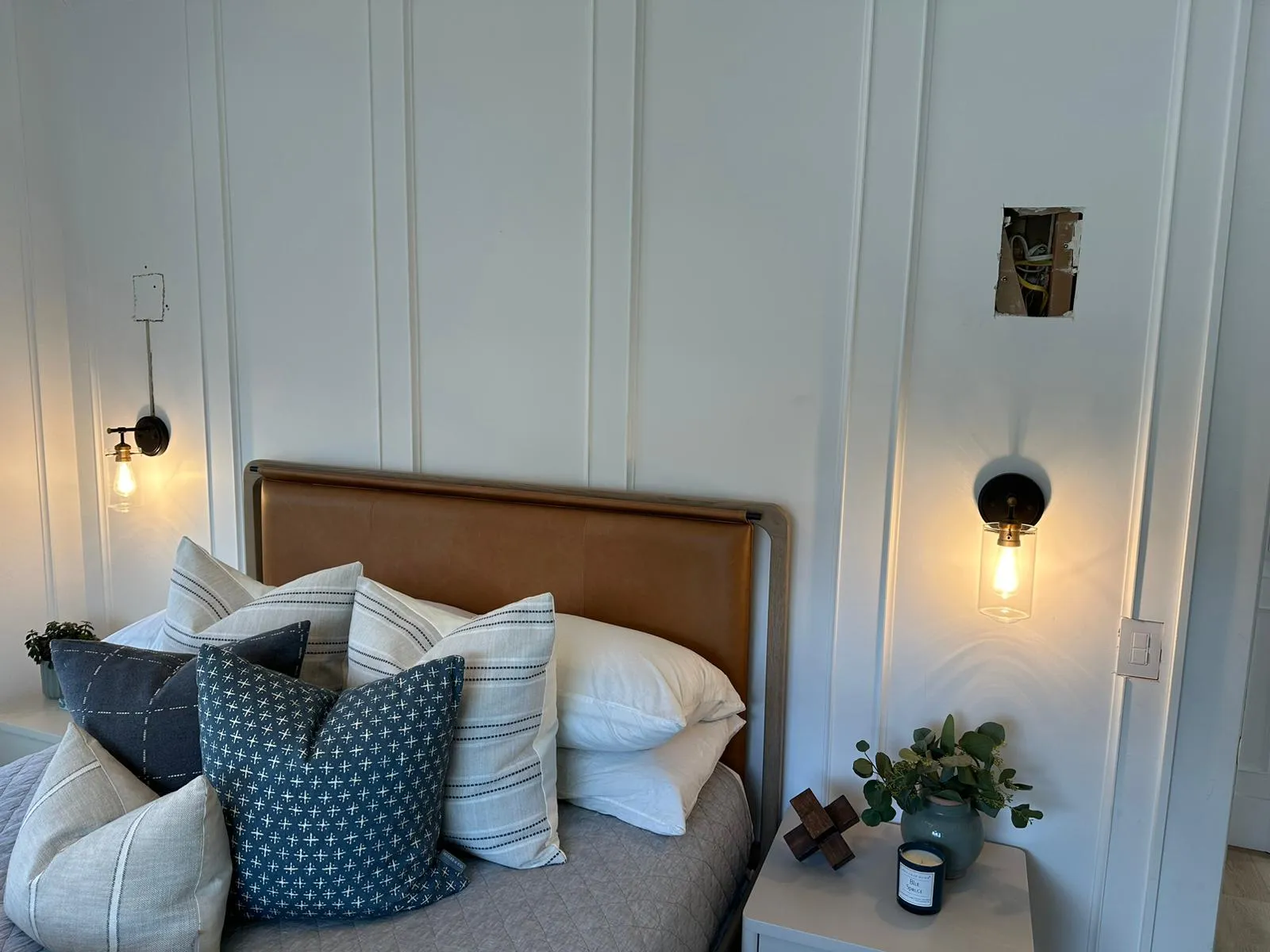 Bedroom with leather headboard and glass-globe sconces. Lighting installation by Martinez Electric Corp