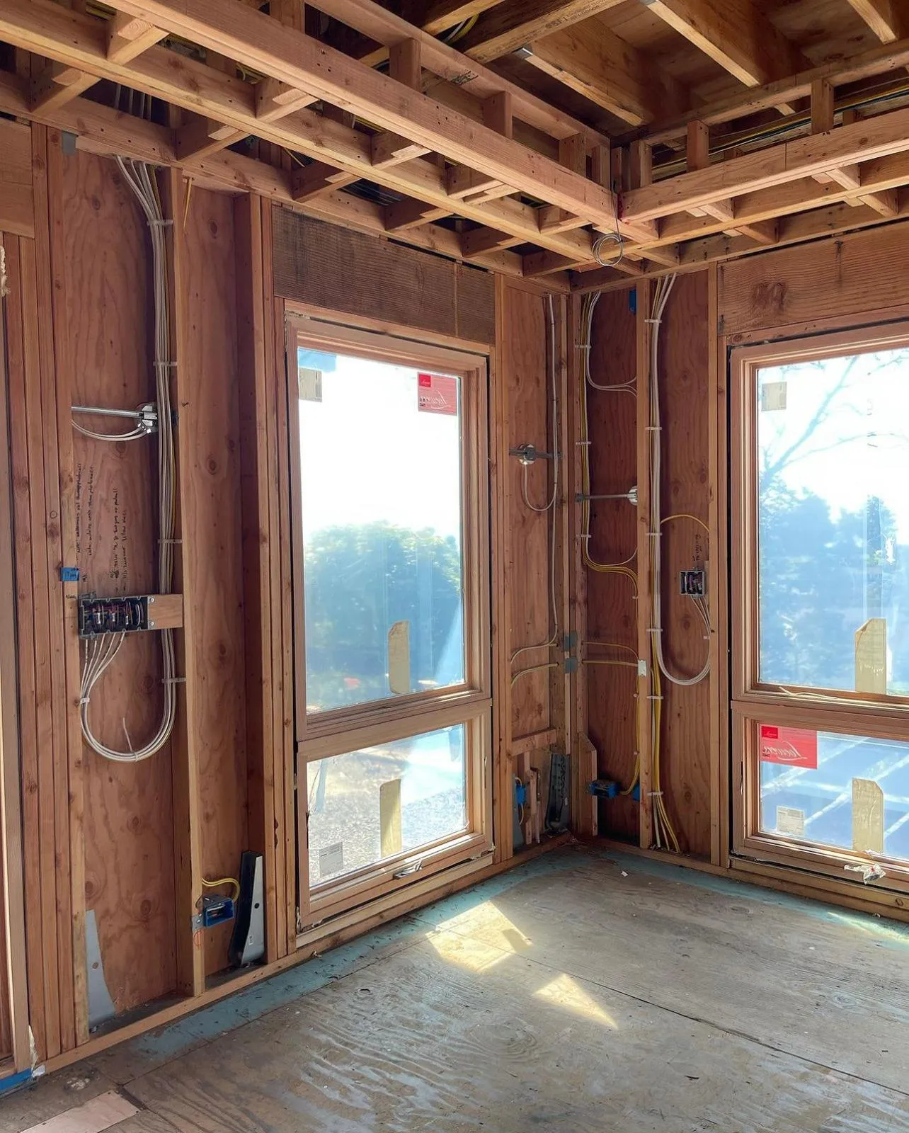 Wall-with-windows rewire: yellow + romex runs over wood framing. Martinez Electric Corp