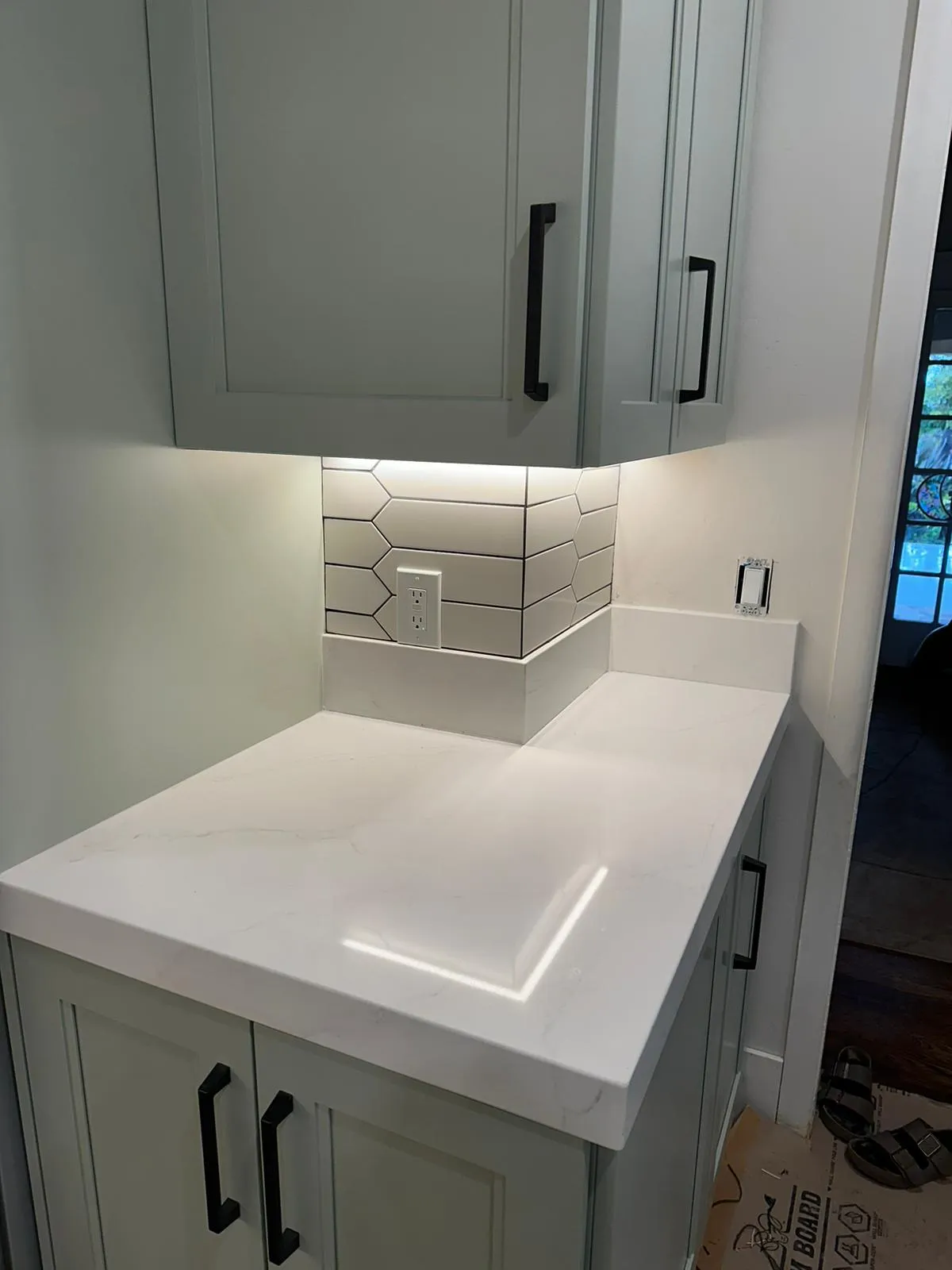 Quartz countertop with picket-tile backsplash and integrated outlet. Under-cabinet lighting by Martinez Electric Corp