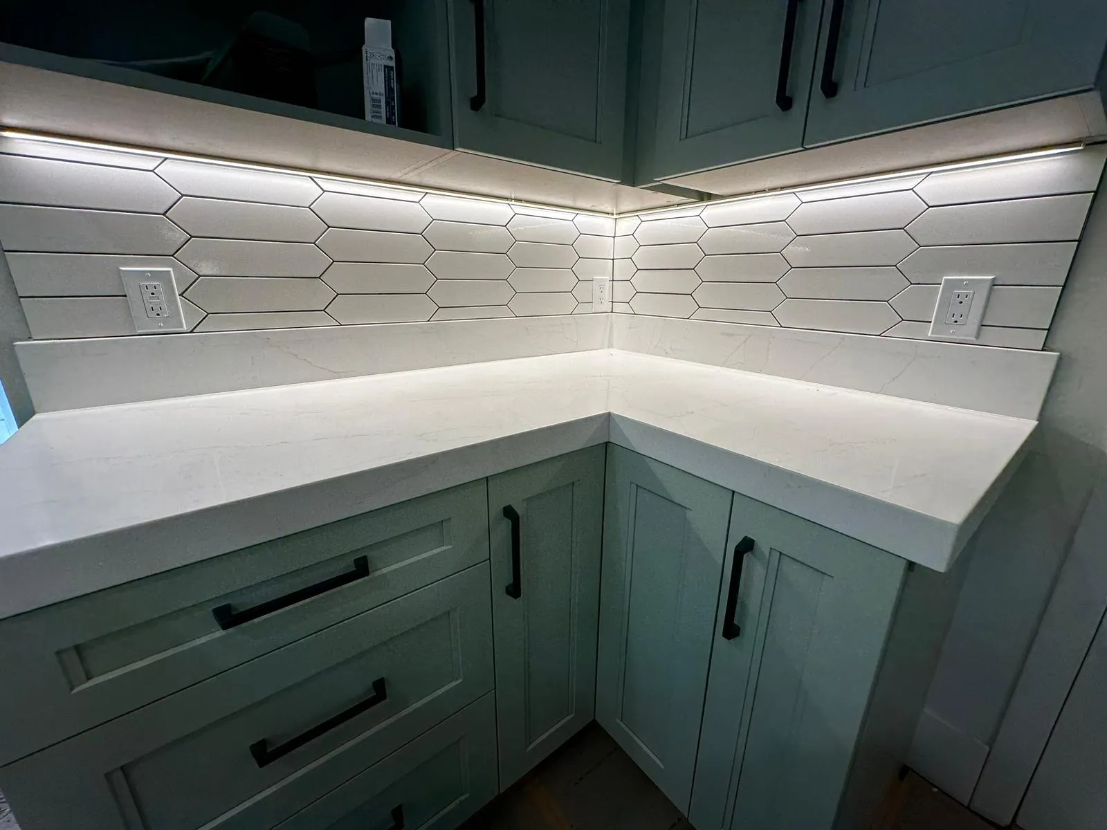White picket-tile backsplash with integrated outlets and under-cabinet LED bar. Martinez Electric Corp