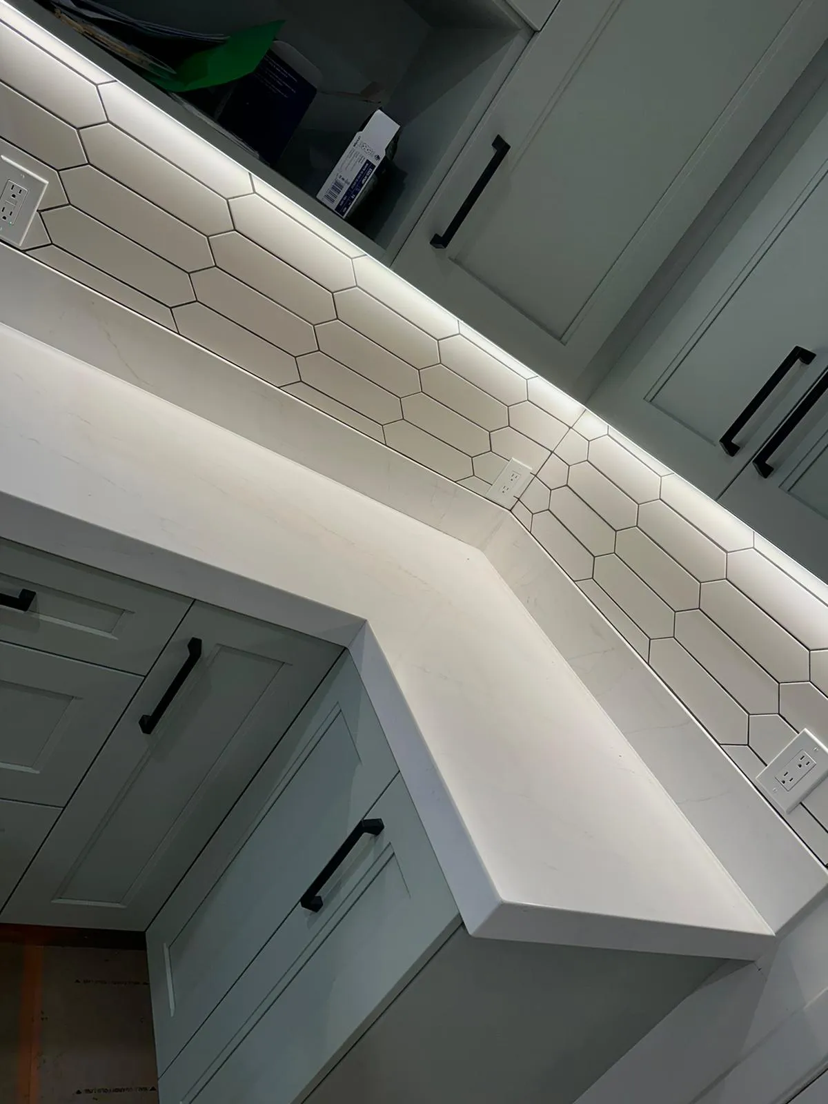 Angled quartz countertop with picket-tile backsplash and integrated outlet. Martinez Electric Corp